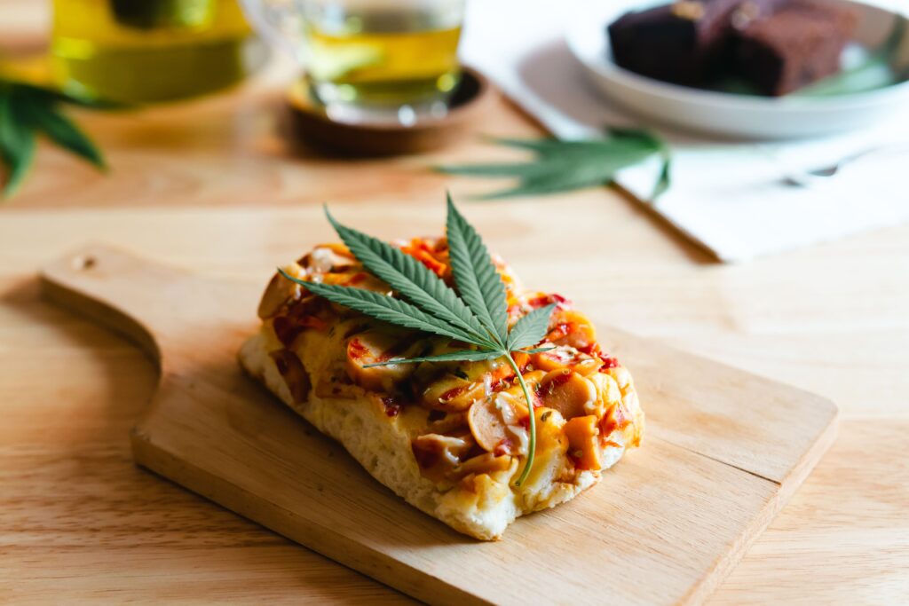 Homemade pizza with marijuana or cannabis leaf on wooden tray.